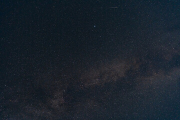 Stunning astrophotography of the night sky featuring the Milky Way galaxy, countless stars, and a single bright, shining planet.