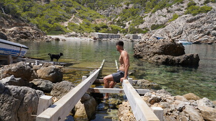 Young man preparing snorkeling gear in remote rocky cove, crystal-clear turquoise water and wild Mediterranean landscape, summer adventure and freedom concept, travel and nature exploration 4K