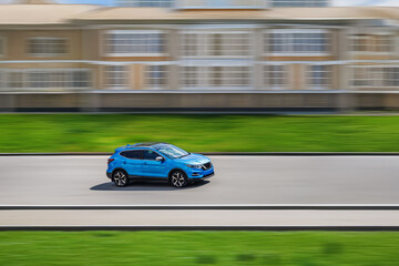Side view of a blue car on a speed blurred background. Fast-moving SUV