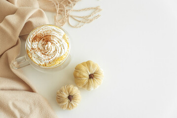 Cozy pumpkin latte with whipped cream and spices, surrounded by autumn decor.