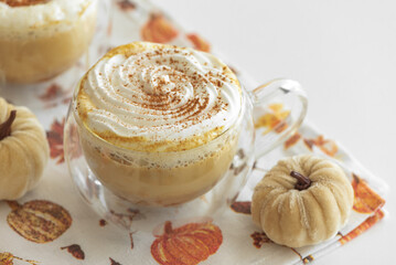 Cozy pumpkin latte with whipped cream and spices, surrounded by autumn decor.