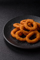 Onion rings or fried squid in breadcrumbs with sauce, takeaway food. Onion rings fried