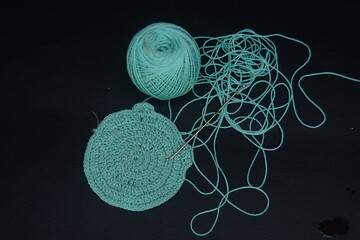 Knitting tools and yarn balls arranged on black background