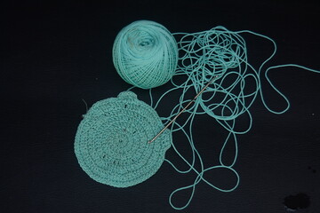 Blue knitting needles and yarn on black surface