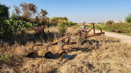 Rusty agricultural equipments, including a plow and a disc harrow, left in a old  farm machinery...
