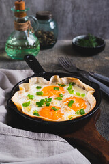 Homemade scrambled eggs in pita bread with herbs in a frying pan on the table vertical view