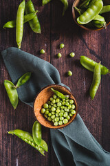 Bowl with green sugar peas on wooden table top and vertical view