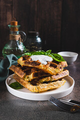 Homemade waffles with sour cream and basil on a plate on the table vertical view