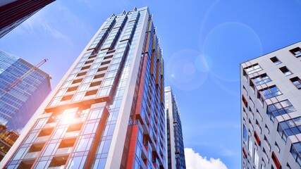 Exterior of a high modern multi-story apartment building - facade, windows and balconies. Timeless glass facade. Modern urban living district.