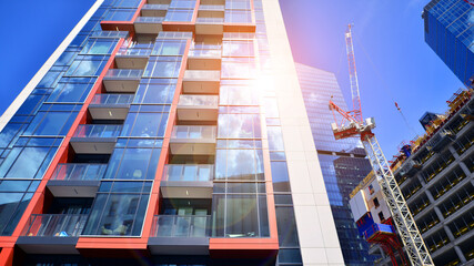 Crane on the construction site in a site surrounded by the high buildings. Office building under construction in the vicinity of high apartment buildings and office building.