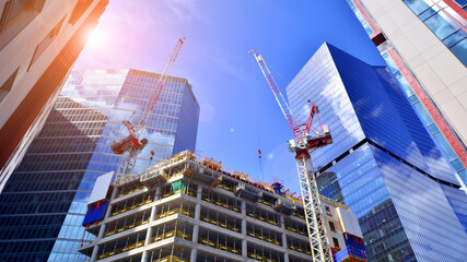 Crane on the construction site in a site surrounded by the high buildings. Office building under construction in the vicinity of high apartment buildings and office building.