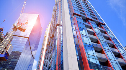 Crane on the construction site in a site surrounded by the high buildings. Office building under construction in the vicinity of high apartment buildings and office building.