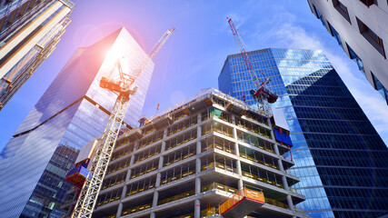 Crane on the construction site in a site surrounded by the high buildings. Office building under construction in the vicinity of high apartment buildings and office building.