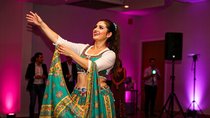 Arabic belly dancer performing joyfully at celebration in vibrant attire  