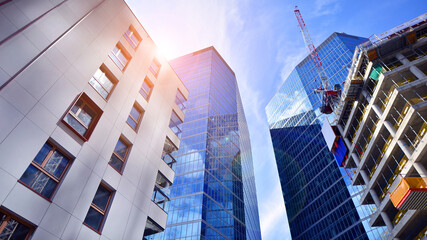 Crane on the construction site in a site surrounded by the high buildings. Office building under construction in the vicinity of high apartment buildings and office building.