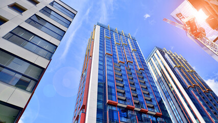 Crane on the construction site in a site surrounded by the high buildings. Office building under construction in the vicinity of high apartment buildings and office building.