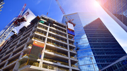 Crane on the construction site in a site surrounded by the high buildings. Office building under construction in the vicinity of high apartment buildings and office building.