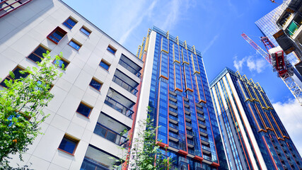 Crane on the construction site in a site surrounded by the high buildings. Office building under construction in the vicinity of high apartment buildings and office building.