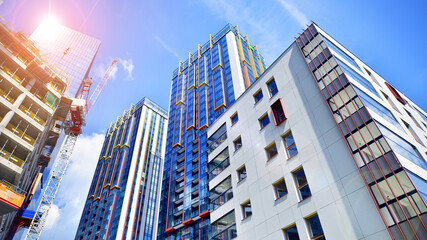 Crane on the construction site in a site surrounded by the high buildings. Office building under construction in the vicinity of high apartment buildings and office building.