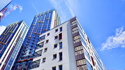 Exterior of a high modern multi-story apartment building - facade, windows and balconies. Timeless glass facade. Modern urban living district.