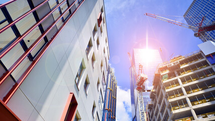 Crane on the construction site in a site surrounded by the high buildings. Office building under construction in the vicinity of high apartment buildings and office building.