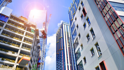Crane on the construction site in a site surrounded by the high buildings. Office building under construction in the vicinity of high apartment buildings and office building.
