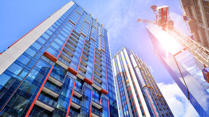 Crane on the construction site in a site surrounded by the high buildings. Office building under construction in the vicinity of high apartment buildings and office building.