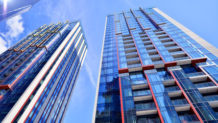 Exterior of a high modern multi-story apartment building - facade, windows and balconies. Timeless glass facade. Modern urban living district.