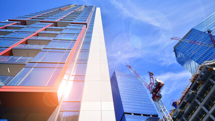 Crane on the construction site in a site surrounded by the high buildings. Office building under construction in the vicinity of high apartment buildings and office building.
