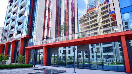 Crane on the construction site in a site surrounded by the high buildings. Office building under construction in the vicinity of high apartment buildings and office building.