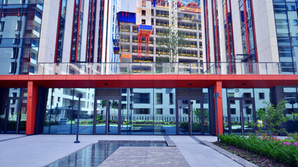Crane on the construction site in a site surrounded by the high buildings. Office building under construction in the vicinity of high apartment buildings and office building.