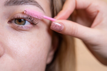 Caucasian woman brushing her eyelashes after lamination. 
