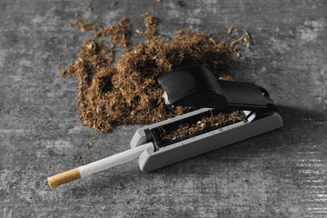 Tobacco rolling tools and a cigarette on a textured surface
