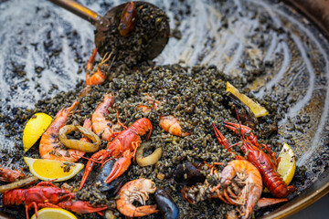 Black paella with seafood. Traditional black paella with shrimps, mussels and calamari served with...