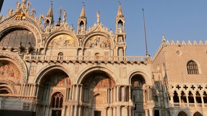 Fototapeta premium Facade of St. Mark's Basilica in Venice, showcasing ornate Italo-Byzantine architecture with golden mosaics, bronze horses, domes, and spires. A masterpiece of religious grandeur and artistic heritage