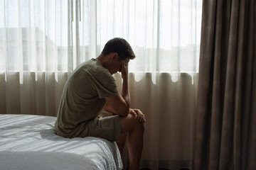 Sad man in a dark room full of desperation thoughts. Portrait of thoughtful sad man alone. Fear, sadness, abuse, depression, addiction.	