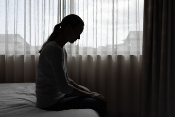 Sad woman in a dark room full of desperation thoughts. Portrait of thoughtful sad female alone....