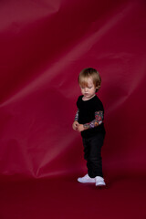 Little boy in studio on red background playing, eating, crying, smiling in black t-shirt with...
