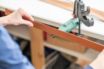 Leatherworker grinding the edge of a strip of leather for a belt in the workshop. 
