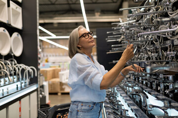 Woman shopping for kitchen fixtures while exploring a home improvement store in a well-lit aisle...