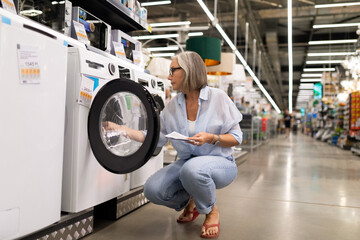 Woman examines washing machine in a home appliance store during the afternoon
