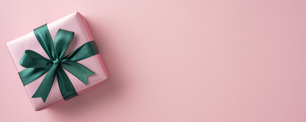 Pink gift box adorned with a green ribbon, placed on a soft pastel background