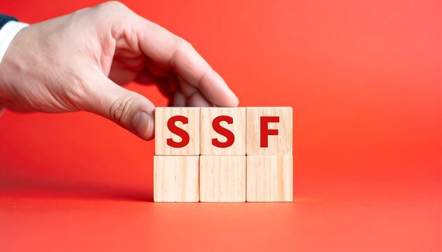 A hand positions wooden blocks spelling out the acronym SSF against a vibrant coral background.
