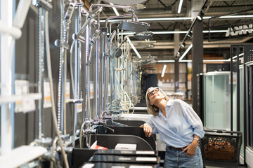 Woman exploring modern bathroom fixtures at home improvement store during a sunny afternoon