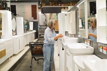 Woman examines bathroom vanities in a home improvement store while shopping in the afternoon