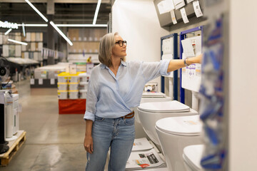 Woman explores bathroom fixtures in a home improvement store during daylight hours