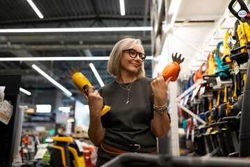 Woman enjoying a moment of choice while shopping for garden tools in a home improvement store in...
