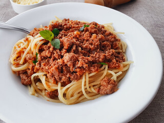 spaghetti bolognese with basil on a white plate