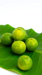 Green citrus fruits on a banana leaf