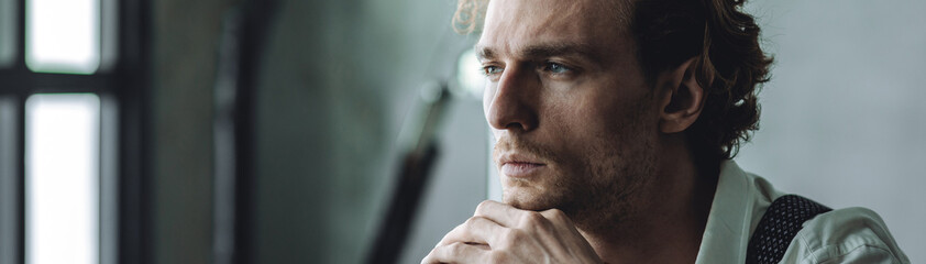 Obraz premium Banner. Portrait of handsome young stylish sexy man in a white shirt, jacket, jeans posing in studio with a loft interior. Black and white. Casual clothes, modern style. Male groom wedding photoshoot